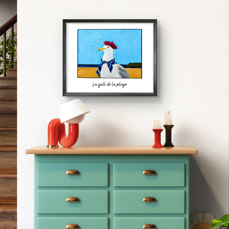 Framed artwork of a seagull on a wall above a teal dresser with decorative items.