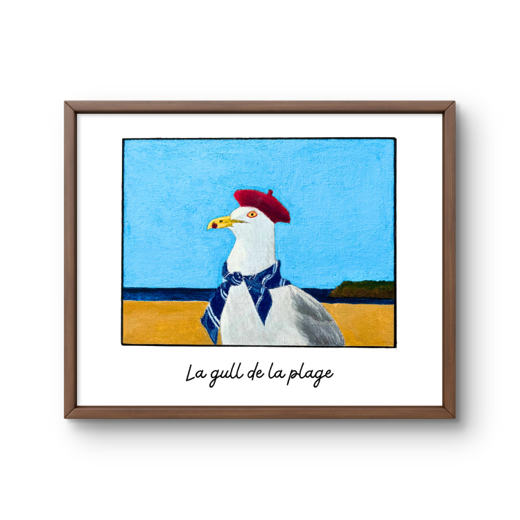 Framed artwork of a seagull wearing a red beret and blue scarf on a beach.